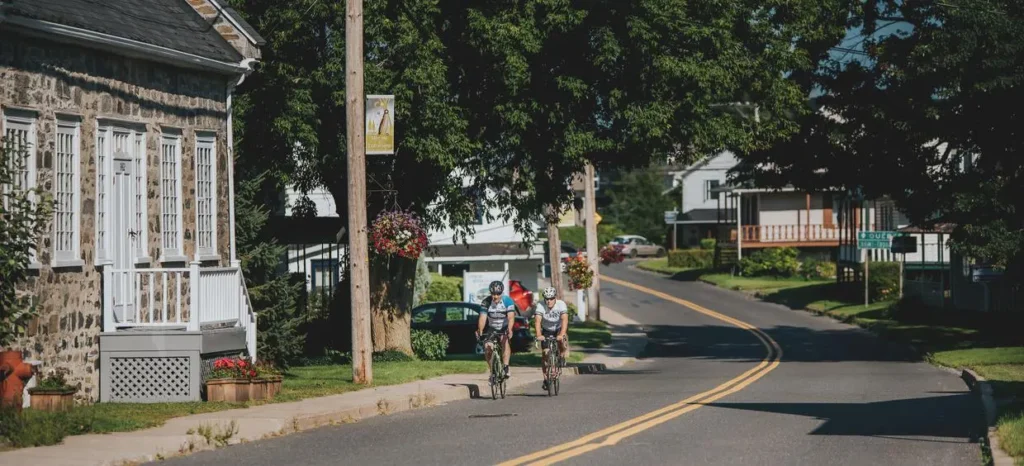 Deux cyclistes sur route de village arboré