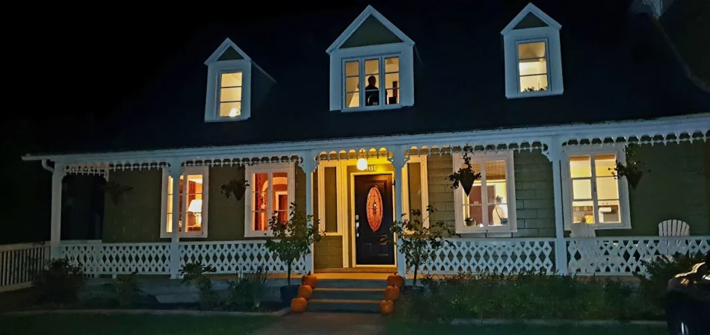 Maison éclairée la nuit avec silhouette à l’étage