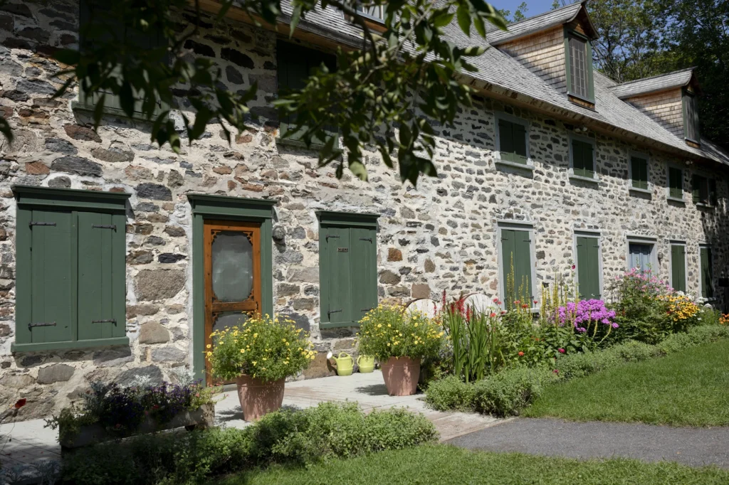 Maison en pierre aux volets verts fleuris